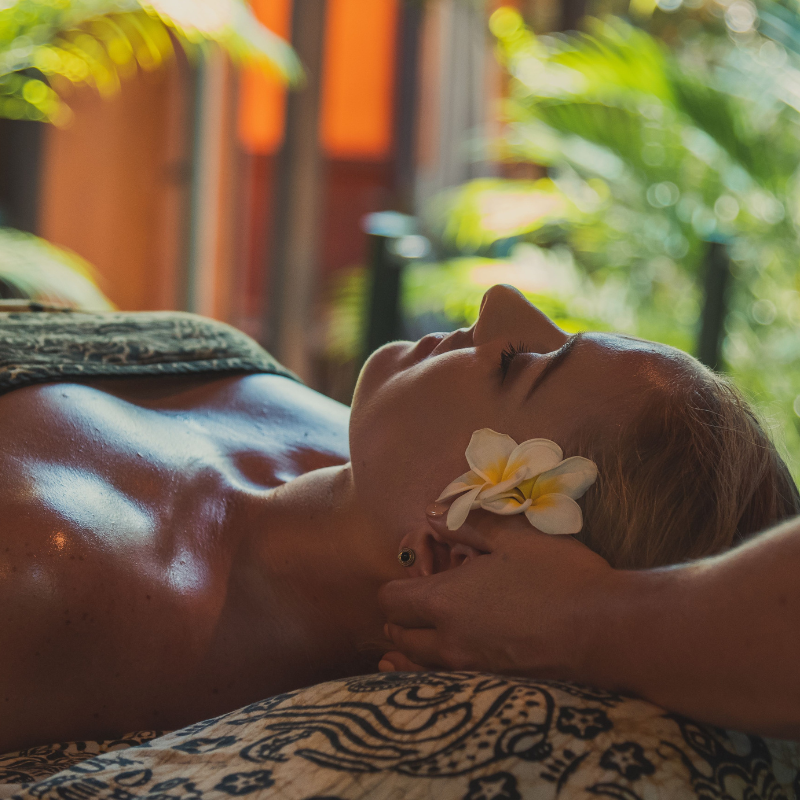 woman getting facial with frangipani in hair